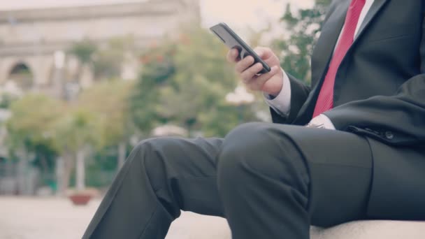 Gros plan portrait Homme barbu sérieux en costume cher tapant quelque chose sur son téléphone alors qu'il était assis sur un banc de parc à l'extérieur — Video