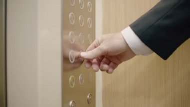 Modern iş ofisindeki asansörü aramak için kırmızı düğmeye basan bir iş adamı. Modern apartman koridorunda asansöre binen bir işletmeci.
