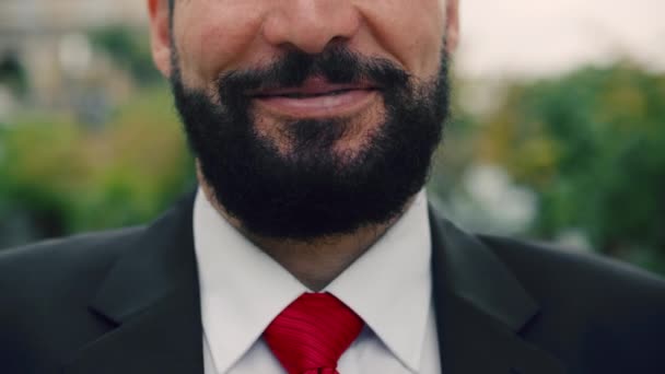 Close-up of a mans chin, an elderly man with a beard, standing in the street, smile while looking at the camera, close-up, slow motion. — Stok Video
