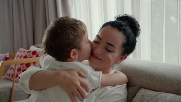 Close-up of a little preschool son kisses and gently hugs his young mother, does not let her out of his embrace, demonstrates his love.Concept of children,family, motherhood,childhood,life, fatherhood — Stock Video