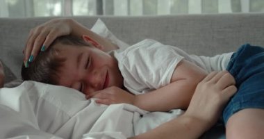 İki anne ve bir oğuldan oluşan mutlu bir aile, kanepede birlikte dinleniyorlar, bu anaokulu öğrencileri annelerinin karnında uyuyorlar, evde sarılıyorlar, anne çocuğun kafasını okşuyor..