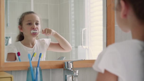 Retrato feliz linda adolescente joven cepillarse los dientes en el baño y sonreír. Rutina diaria de salud infantil. Niño caucásico con diente blanco mirando el espejo aislado en casa. Estilo de vida. — Vídeo de stock