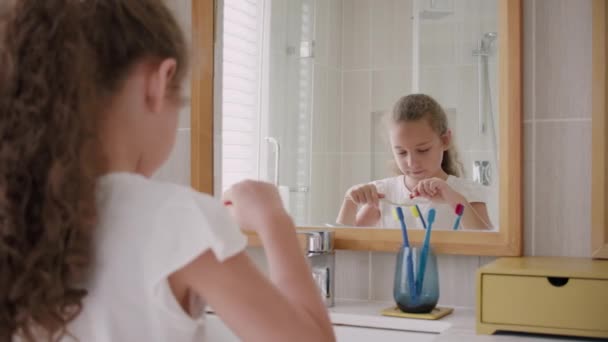 Retrato feliz bonito jovem adolescente espremendo pasta de dentes em escova de dentes em seu banheiro.Crianças rotina de cuidados de saúde diária. Miúdo caucasiano com dente branco a olhar para o espelho isolado em casa. Estilo de vida — Vídeo de Stock