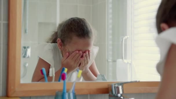 Portrét šťastný roztomilý mladý dospívající dívka umyje si obličej v koupelně a usmívání.Děti každodenní zdravotní péče rutina. Kavkazská holčička s pohledem na zrcadlo omývá jeho tvář osamělý doma.Životní styl — Stock video