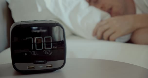 Solrig morgen, søvnig kaukasisk vågner om morgenen, slukker for vækkeuret, som er på natbordet for at falde i søvn, nærbillede – Stock-video