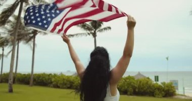 Vatanseverlik, bağımsızlık günü ve tatil konsepti. Yaz mevsiminde ulusal Amerikan bayrağıyla mayolu mutlu bir genç kadın..