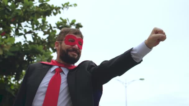 Portrait sénior homme d'affaires barbu souriant positif en manteau rouge et verres de super-héros. Homme d'affaires heureux confiant, leader se faisant passer pour un super-héros simulent voler avec la main tendue dans le poing devant. — Video