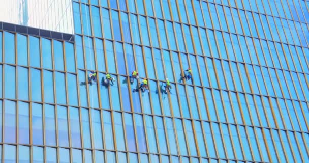 Hat férfi munkások piros és sárga munkaruhában takarítás a külső ablakok egy üzleti felhőkarcoló - ipari alpinizmus.high-rise emberek mossa ablakok.Koncepció takarítás — Stock videók