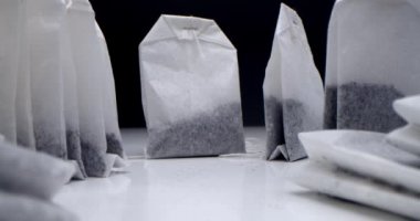 Siyah arka planda beyaz bir masanın üzerinde çay poşetleri var. Sabah çayı yapıyorum. Çay klipsi için makro atış aşçılık ve aşçılık projeleri için uygundur.