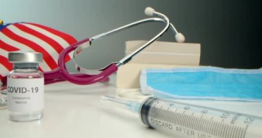 COVID-19 aşısı geliştirildi, koronavirüs aşısı ampulü ve çeşitli şırıngalar, tıbbi aletler, yüz kalkanı, Amerikan bayrağı geçmişi ve kitapları geliştirildi..
