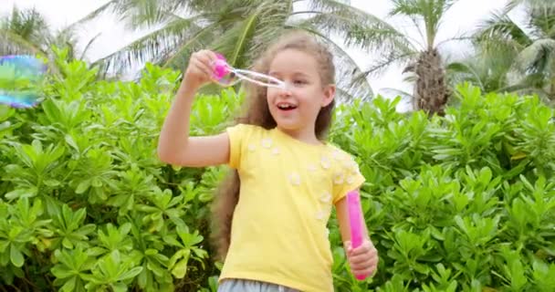 Criança branca bonito, criança feliz soprando bolhas de sabão em um parque. Close up menina feliz desfrutando e fazendo bolhas de sabão. — Vídeo de Stock