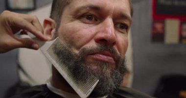 Profesyonel berber, müşteri sakalını ustura ile tıraş eder. Berber dükkanında eski moda bıçakla kesilmiş bir sakal. Sakalını kuaförde kestirecek yakışıklı bir adam..