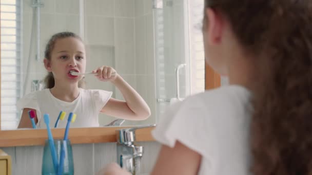 Porträtt glad söt ung tonåring flicka borsta tänderna i badrummet och ler. Barn daglig sjukvård rutin. Vit grabb med vit tand tittar på spegeln isolerad hemma. Livsstil. — Stockvideo