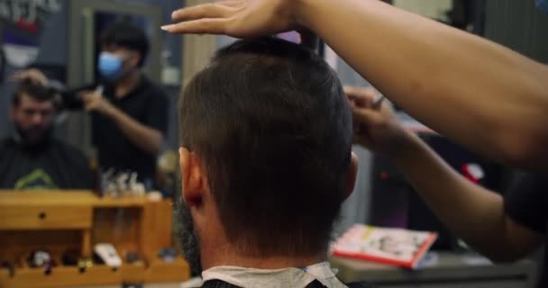 Un parrucchiere professionista fa una striscia di capelli e barba al cliente. Barba tagliata al barbiere. Un bell'uomo in un barbiere si rasa la barba in un barbiere. — Video Stock