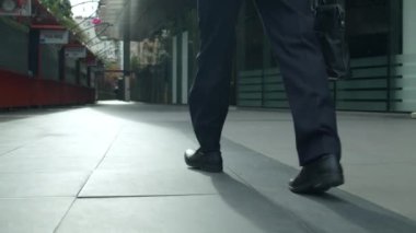 4K çekimi, güneşli bir yaz gününde, şehir merkezinde bir caddede yürüyen lüks elbiseli bir işadamının etrafında ağır çekimde hareket eder. Kavram işadamı, teknoloji, iletişim, başarı.