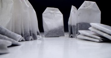 Süper makro çay poşetleri beyaz bir masada siyah bir arka planda. Sabah çayı yapıyorum. Çay klipsi için makro atış aşçılık ve aşçılık projeleri için uygundur.