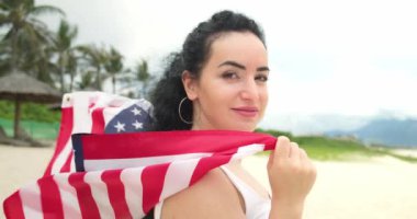 Vatanseverlik, bağımsızlık günü ve tatil konsepti. Yaz mevsiminde ulusal Amerikan bayrağıyla mayolu mutlu bir genç kadın..