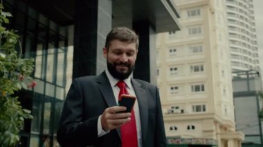 Sokakta bir adam cep telefonuyla konuşuyor. Bir metropolün finans bölgesinde lüks giysiler içinde ciddi bir orta yaşlı işadamı görüşmeler için cep telefonu kullanıyor. 4K