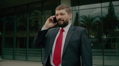 Sokakta bir adam cep telefonuyla konuşuyor. Bir metropolün finans bölgesinde lüks giysiler içinde ciddi bir orta yaşlı işadamı görüşmeler için cep telefonu kullanıyor. 4K