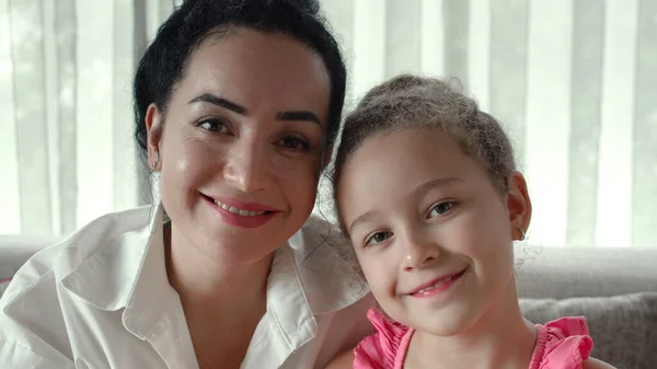 Güzel, gülümseyen bir kız çocuğu anne kameraya bakar. Portre Mutlu aile genç bekar anne koruyucu anne ve tatlı kız kucaklaşması tatlı aşk konsepti