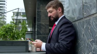 İş adamı sokakta mesaj atıyor. Bir metropolün finans bölgesinde lüks giysiler içinde ciddi bir orta yaşlı işadamı görüşmeler için cep telefonu kullanıyor. 4