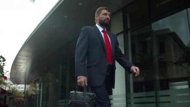 Senior zakenman in een duur pak met een aktetas in zijn hand loopt langs de stad straat op zonnige zomerdag, slow motion. Zakenman loopt op straat — Stockvideo