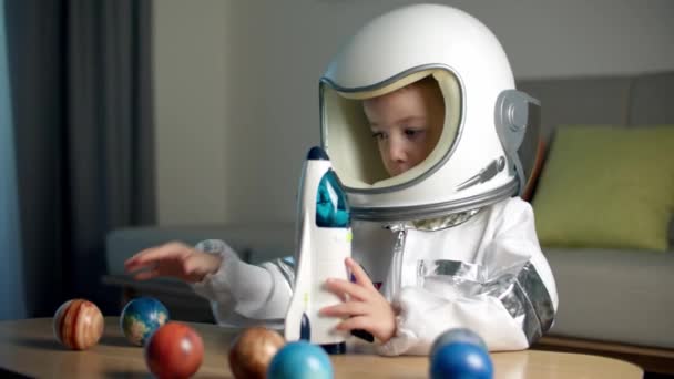 Dziecko bawi się w domu w astronaucie, zabawny portret dziewczynki 8-9 lat w zabawkowym skafandrze kosmicznym, uśmiechnięte dziecko, wystrzeliwuje rakietę kosmiczną, zbliżenie, pilota podróżującego w kosmosie. Szczęśliwego dzieciństwa — Wideo stockowe