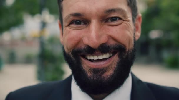 Retrato feliz empresário sênior em um terno caro em um astylish, um empresário sênior barbudo bonito fica na rua ao lado de um edifício de negócios e olha para a câmera sorrindo. — Vídeo de Stock
