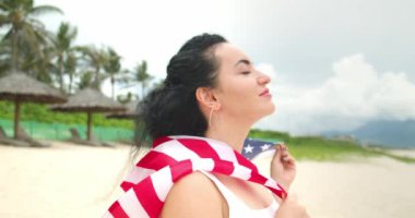 Vatanseverlik, bağımsızlık günü ve tatil konsepti. Yaz mevsiminde ulusal Amerikan bayrağıyla mayolu mutlu bir genç kadın..