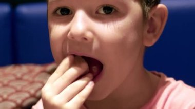 Küçük şirin çocuk masada oturur ve egzotik meyveler yer, bebek isteyerek yer. Mutlu bir çocukluk kavramı..