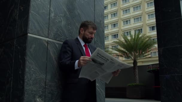 Un homme d'affaires sérieux d'âge moyen en vêtements de luxe dans le quartier financier d'une métropole utilise la presse d'information du journal près de l'immeuble d'affaires. Concentration douce — Video