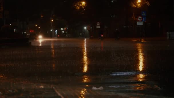 Close-up à noite, gotas de verão ou outono chuva cair sobre o asfalto na cidade, transformando-se em uma grande poça, inundando a rua. As inundações são a estação chuvosa e chuvas fortes. As gotas de chuva estão a cair. — Vídeo de Stock