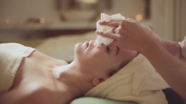 Sağlık hizmeti vücut masajı spa konsepti. Genç, beyaz, güzel bir kadın güzellik salonundaki masaj terapistinden yüz masajı yaptırıyor..