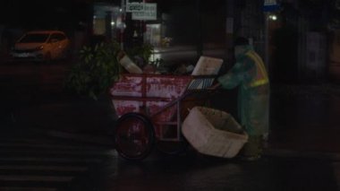 A cleaning oldman on the street removes garbage. Cleanliness and order in the yard depends on the janitor during quarantine.Rainwater flows on the road and fall into the metal hatch with holes drain.