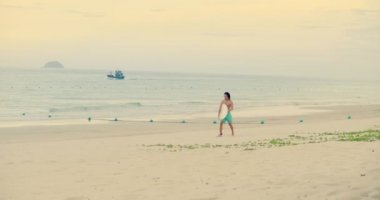 Kimliği belirsiz Asyalı bir sporcu sörf tahtasıyla yürüyor. Atlet, sörf yaptıktan sonra dalgaların üzerinde süzülüyor. Han Hoa Eyaleti, Vietnam, 27 Eylül 2021