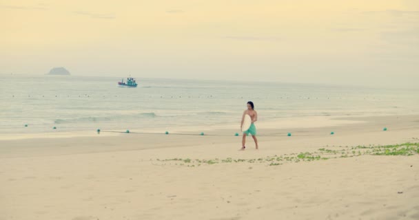 An unknown asian man sportsman-surfer walks with a surfboard. The athlete is plowing from the sea, going from the rides on the waves after surfing.Han Hoa Province, Vietnam, September 27, 2021 — Vídeo de Stock