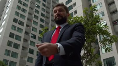 Şehir merkezinde başarılı, orta yaşlı bir işadamı bir iş toplantısı için bekliyor. İş ortakları, iletişim ve başarı ile iş toplantısını yakalamak için saatine bakıyor..