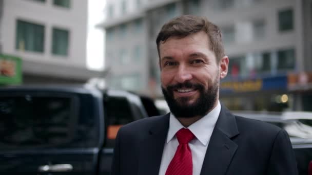 Portrait happy senior businessman in an expensive suit in a in a stylish, a handsome bearded senior businessman stands on the street next to a buildings and looks into the camera. — Vídeo de Stock