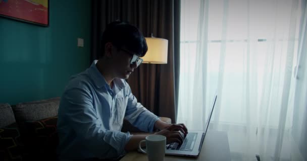 Νέοι ελκυστική ασιατική Βιετνάμ άνθρωπος απασχολημένος υπολογιστή εργασίας ή έξυπνο tablet στο φορητό υπολογιστή στο σπίτι σε freelance αναλυτής δεδομένων, επιστήμονας της επιστήμης των δεδομένων για τις επιχειρήσεις. — Αρχείο Βίντεο
