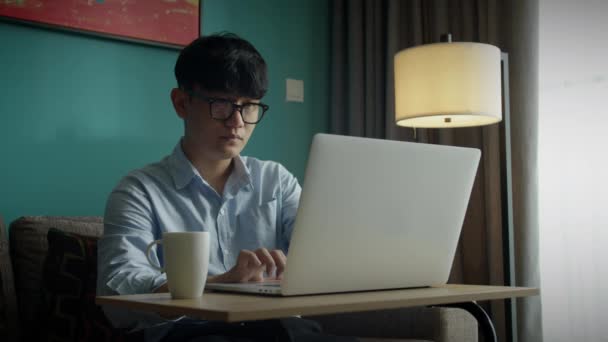Jovem atraente asiático vietnam homem ocupado trabalho computador ou tablet inteligente no laptop em casa em freelance analista de dados, cientista de ciência de dados para negócios. — Vídeo de Stock