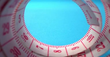 Arka plandaki dikiş ve renkli iplik rulosunun içine bir mezuranın süper makro çekimi. Giysi fabrikası. İğne, iplik, mezura, renkli iplikler çerçevede görünür..