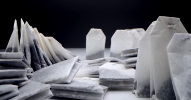 Siyah arka planda beyaz bir masanın üzerinde çay poşetleri var. Sabah çayı yapıyorum. Çay klipsi için makro atış aşçılık ve aşçılık projeleri için uygundur.