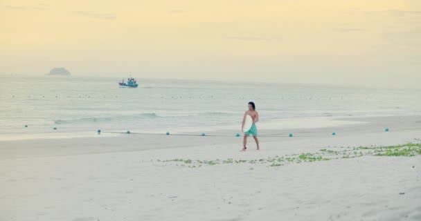Provincia di Han Hoa, Vietnam, 27 settembre 2021. L'atleta sta arando dal mare, passando dalle giostre sulle onde dopo il surfista.Uno sconosciuto sportivo-surfista asiatico cammina con una tavola da surf. — Video Stock