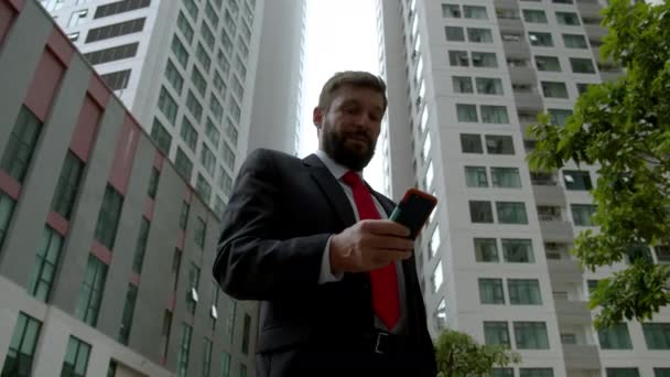 A serious middle-aged businessman in luxurious clothes in the financial district of a metropolis uses reads the news press from the newspaper near the business building. — Wideo stockowe