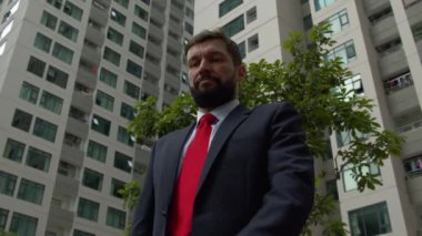 Şehir merkezinde başarılı, orta yaşlı bir işadamı bir iş toplantısı için bekliyor. İş ortakları, iletişim ve başarı ile iş toplantısını yakalamak için saatine bakıyor..