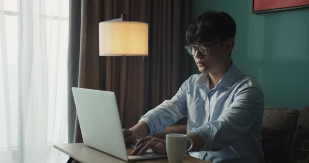 Jeune vietnam asiatique attrayant homme occupé ordinateur de travail ou tablette intelligente sur ordinateur portable à la maison en freelance analyste de données, science des données scientifique pour les entreprises. — Video