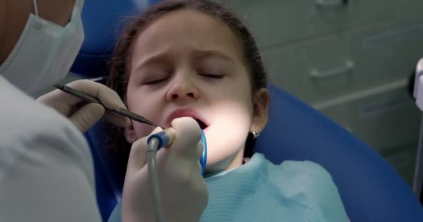 Οδοντίατρος στο οδοντιατρικό γραφείο, οδοντίατρος γυναίκα που θεραπεύει δόντια σε μικρό κοριτσάκι ασθενή στην κλινική. Γυναίκα επαγγελματίας γιατρός Στοματολόγος στην εργασία. Έννοια οδοντιατρικός έλεγχος. — Αρχείο Βίντεο