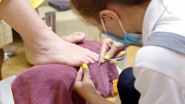 Косметолог робить процедуру, готує і лікує клієнтів за допомогою рідини, щоб видалити старий лак для нігтів з пальців перед педикюром . — стокове відео