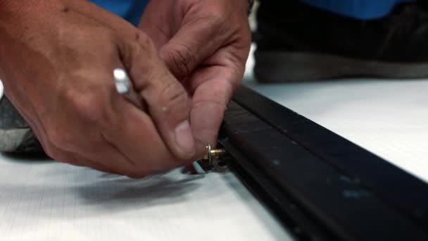 Ręce pracownika, który odkręca śrubę kluczem z metalowej ramy. Mężczyzna używa metalowego klucza, żeby wyjąć śrubę z kawałka metalu w stolarni.. — Wideo stockowe