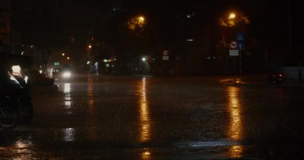 Gros plan la nuit, des gouttes de pluie d'été ou d'automne tombent sur l'asphalte de la ville, se transformant en une grande flaque d'eau, inondant la rue. Les inondations sont la saison des pluies et de fortes pluies. Des gouttes de pluie tombent. — Video